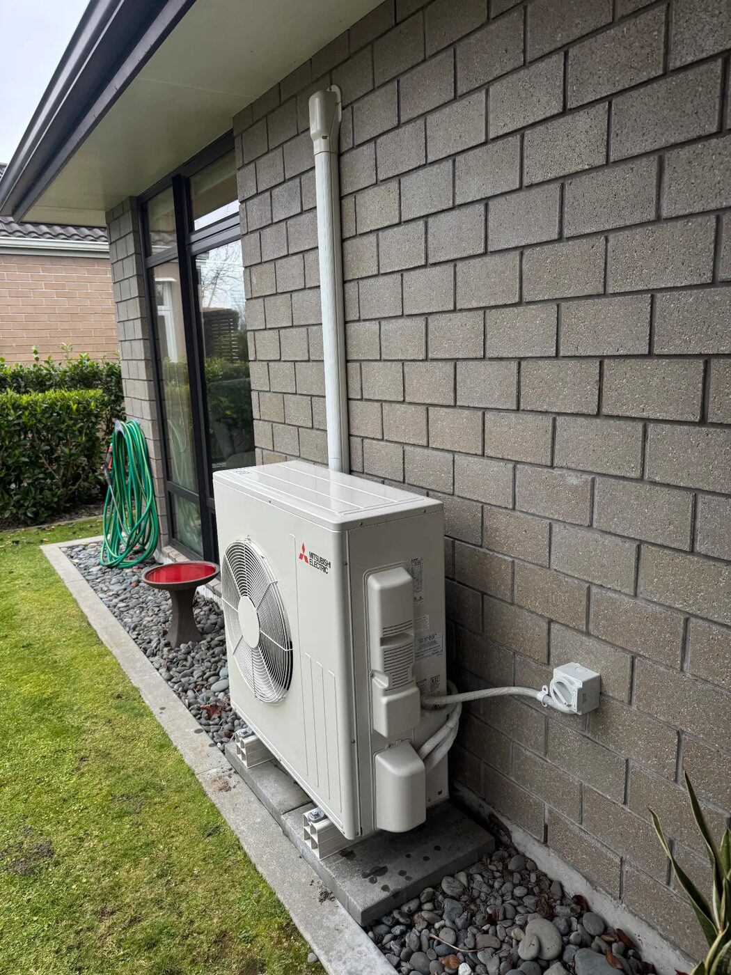 Mitsubishi Electric heat pump outdoor unit neatly installed on a block wall